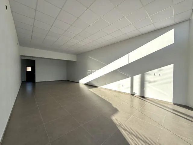 Interior de uma sala ampla com piso de concreto e teto de grid.