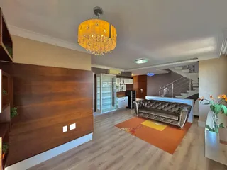 Sala de estar com piso de madeira e sofá no interior de uma residência.