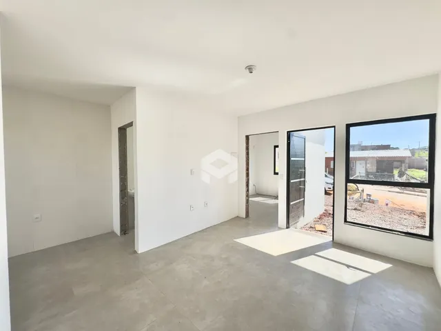 Vista interna de um ambiente vazio com paredes brancas e piso de concreto.