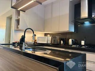A cozinha moderna apresenta armários brancos e bancadas escuras.
