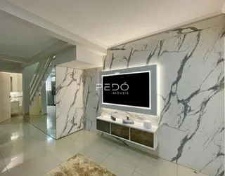 Interior de um hall com paredes em mármore e escadaria em uma residência.