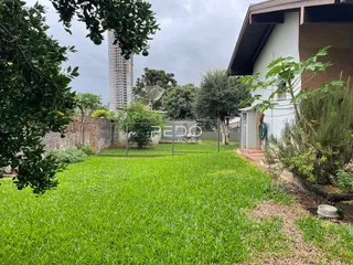 Vista externa de uma propriedade com gramado verde e cerca no Brasil.