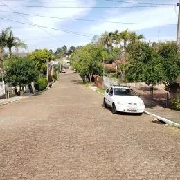 Vista de uma rua asfaltada em uma área residencial com árvores ao longo da via.