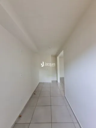 Corredor interno de uma residência com piso de cerâmica e paredes brancas.