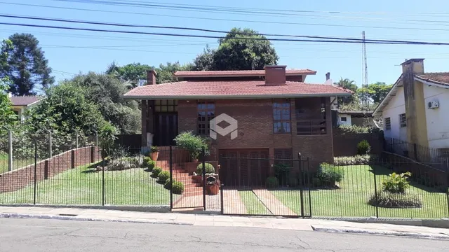 Fachada de uma casa de tijolos com cerca e jardim na rua.