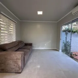 Foto de uma sala de estar com sofá e janela lateral.