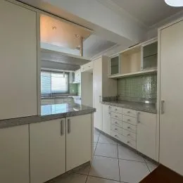Foto de uma cozinha com armários brancos e bancadas claras.