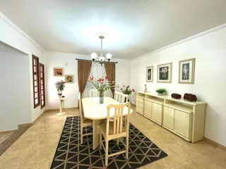 Ambiente interno de uma sala de jantar com paredes brancas e piso de madeira.
