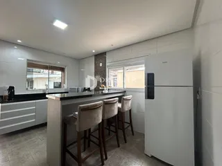 Vista da cozinha com armários brancos e bancadas escuras.