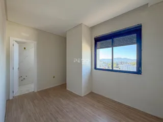 Ambiente interno com piso de madeira e grande janela com vista para a paisagem.