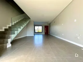 Corredor interno com piso de cerâmica e escadaria de vidro.