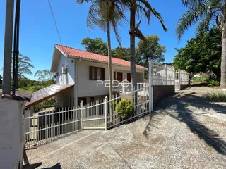 Fachada de uma casa em Lajeado, Brasil, com cerca branca e paisagismo.