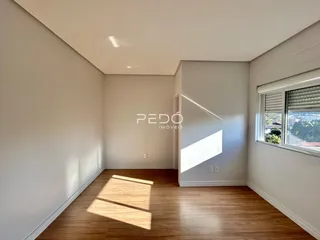 Ambiente interno de uma sala com piso de madeira e luz natural.