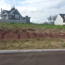 Paisagem de terra vermelha e vegetação em uma área externa.