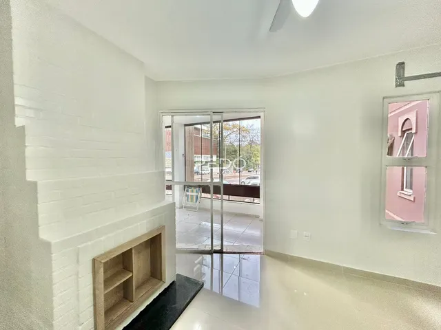 Interior de uma sala clara com piso de cerâmica e parede branca.