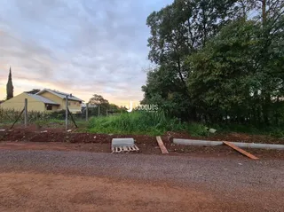 Vista externa de uma propriedade com vegetação densa ao fundo.