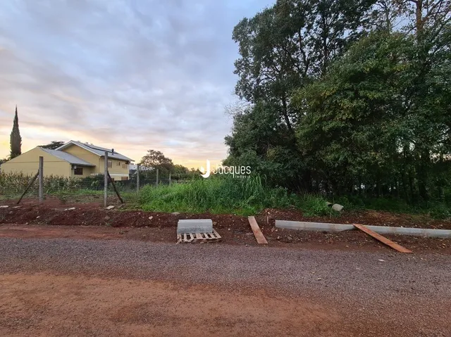 Vista externa de uma propriedade com vegetação densa ao fundo.