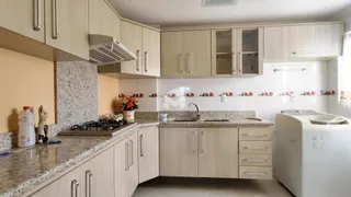 Cozinha com armários de madeira clara e bancadas de granito.