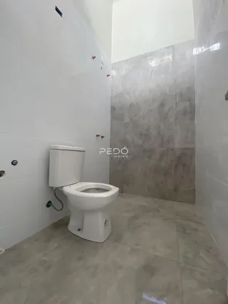 Foto de um banheiro com revestimento branco e piso cinza claro.