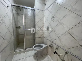 Foto de um banheiro com revestimento de cerâmica e box de vidro.