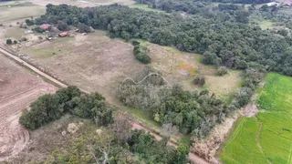 Vista aérea de uma área rural com campos e vegetação densa.