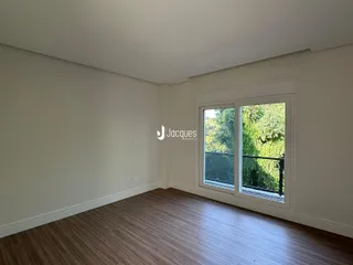 Ambiente interno de uma sala com piso de madeira e janela.