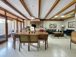 Sala de jantar e estar com pé direito alto e vigas de madeira expostas.