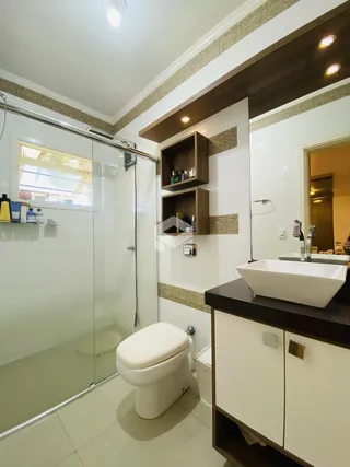 Banheiro moderno com box de vidro e revestimento de cerâmica.