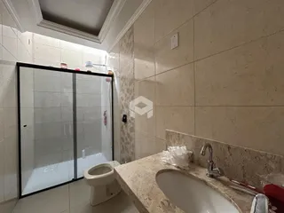 Banheiro com box de vidro e bancada de mármore.