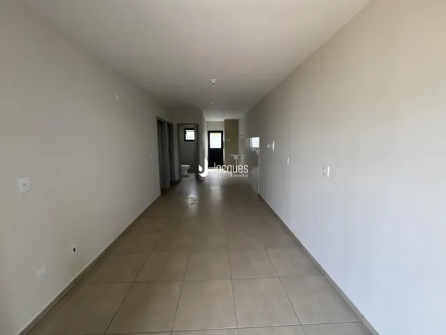 Corredor interno de uma residência com paredes brancas e piso de cerâmica.