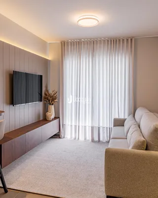Sala de estar moderna com sofá e televisão em um ambiente claro.
