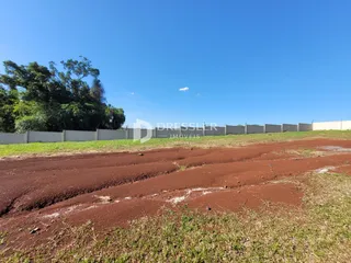Vista da propriedade com cerca e vegetação ao fundo.
