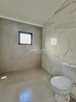 Foto do interior de um banheiro com piso de cerâmica e parede de mármore.