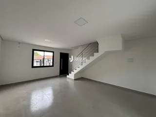 Esta é uma sala de estar ampla com piso claro e uma escadaria.