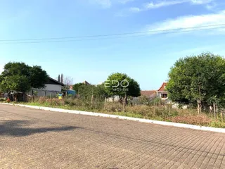 Vista externa de uma propriedade com vegetação e estrada no primeiro plano.
