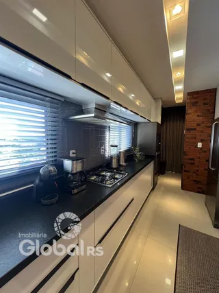 Vista da cozinha moderna com armários brancos e bancadas escuras.