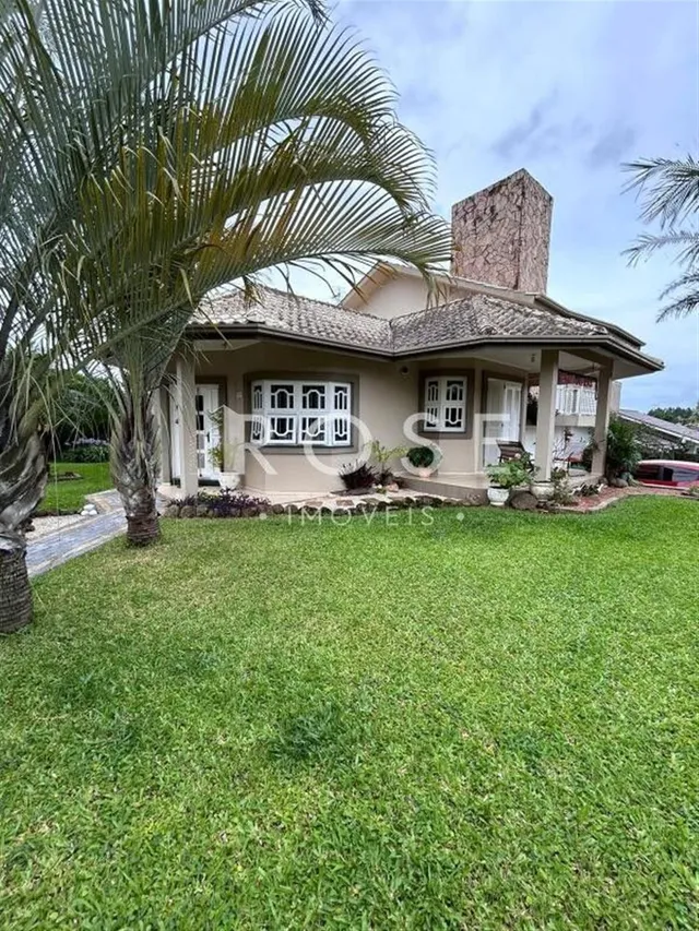Fachada de uma casa em Lajeado, Brasil, com gramado verde e palmeiras.