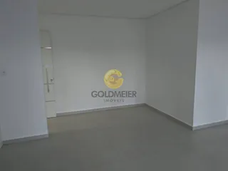Ambiente interno vazio com paredes brancas e piso claro.