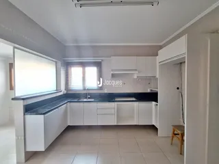 Uma cozinha moderna com armários brancos e bancadas escuras.