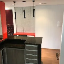 Vista de uma cozinha com armários escuros e bancadas em um ambiente interno.