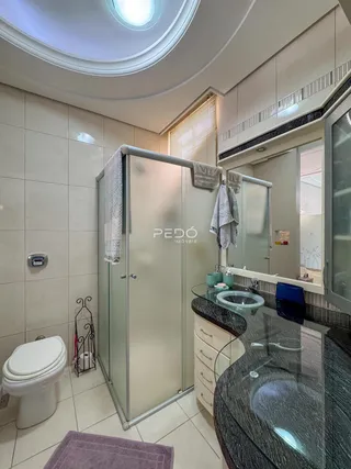 Interior de um banheiro moderno com revestimento cerâmico e box de vidro.