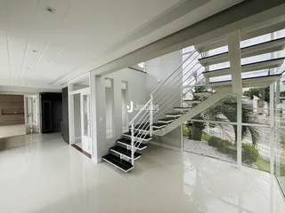 Hall de entrada moderno com escadaria e guarda-corpo de vidro.