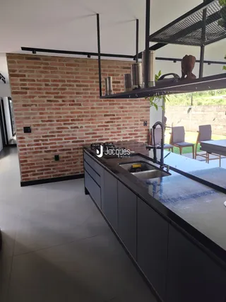 Vista da cozinha com paredes de tijolo aparente e armários escuros.