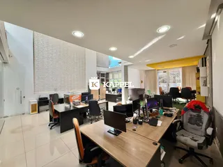 Uma sala de escritório moderna com mesas de trabalho e computadores.