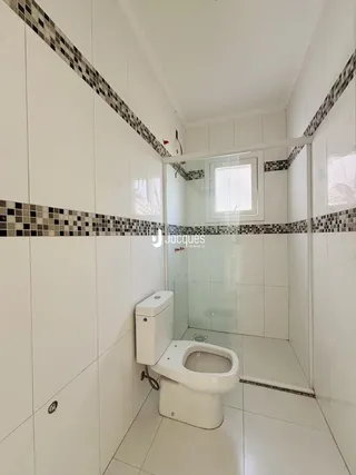 Foto de um banheiro com revestimento de azulejos brancos e escuros.