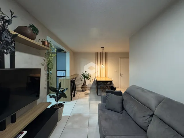 Sala de estar com piso de cerâmica e sofá cinza em um imóvel em Lajeado.
