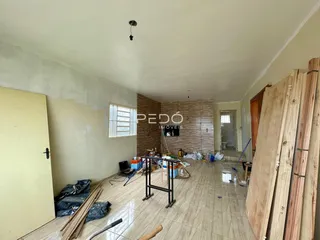 Interior de uma sala com piso de cerâmica e materiais de construção visíveis.