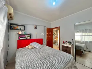 Quarto com cama de cabeceira vermelha e roupa de cama cinza.