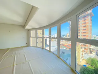 Vista panorâmica de um ambiente interno com grandes janelas que oferecem uma vista da cidade.