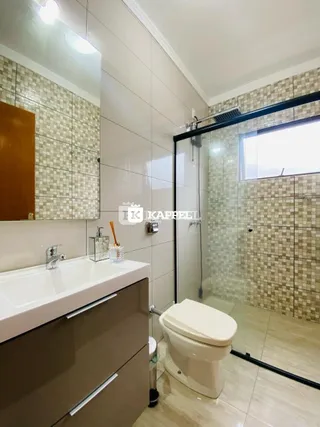 Foto de um banheiro com revestimento de azulejos e box de vidro.